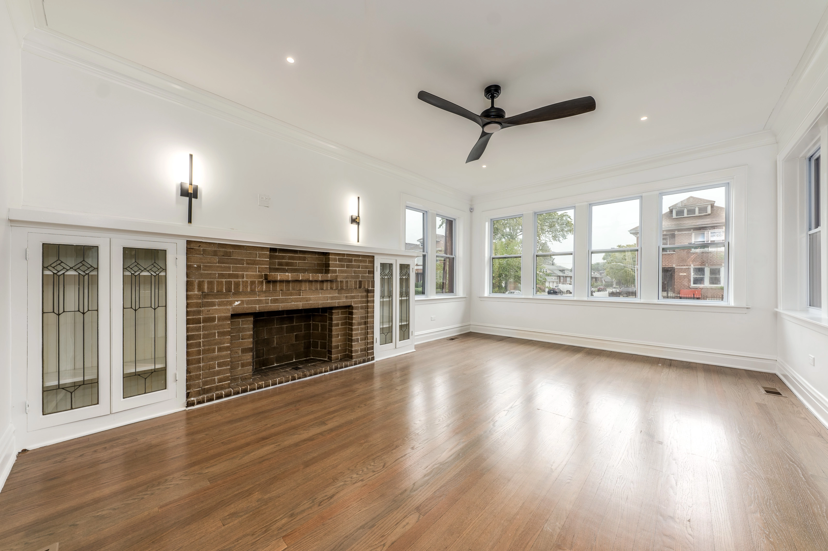Living room with two sconce lights over fireplace and recessed lights on ceiling