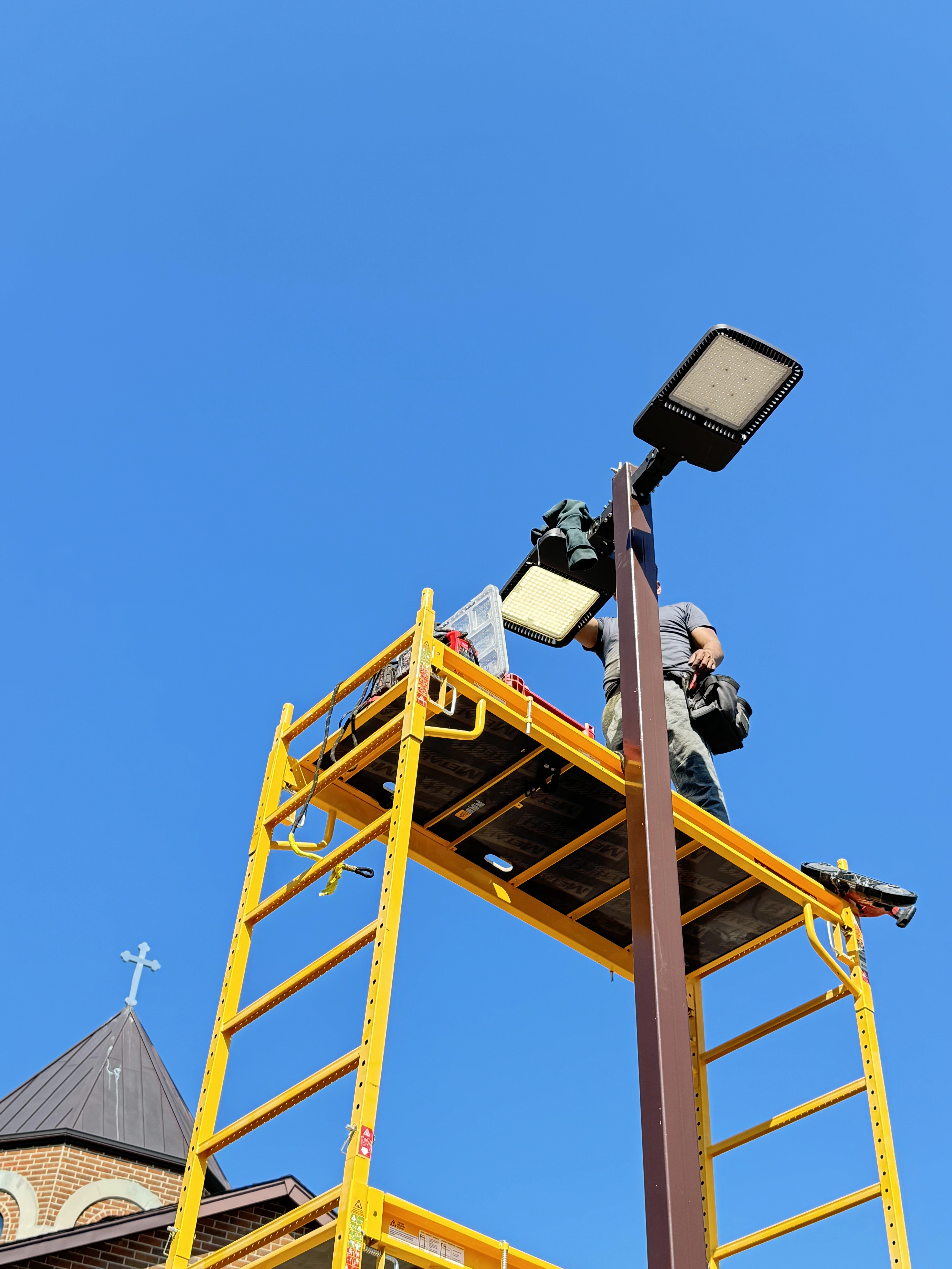 Electrician on scaffolding platform working on street lamp