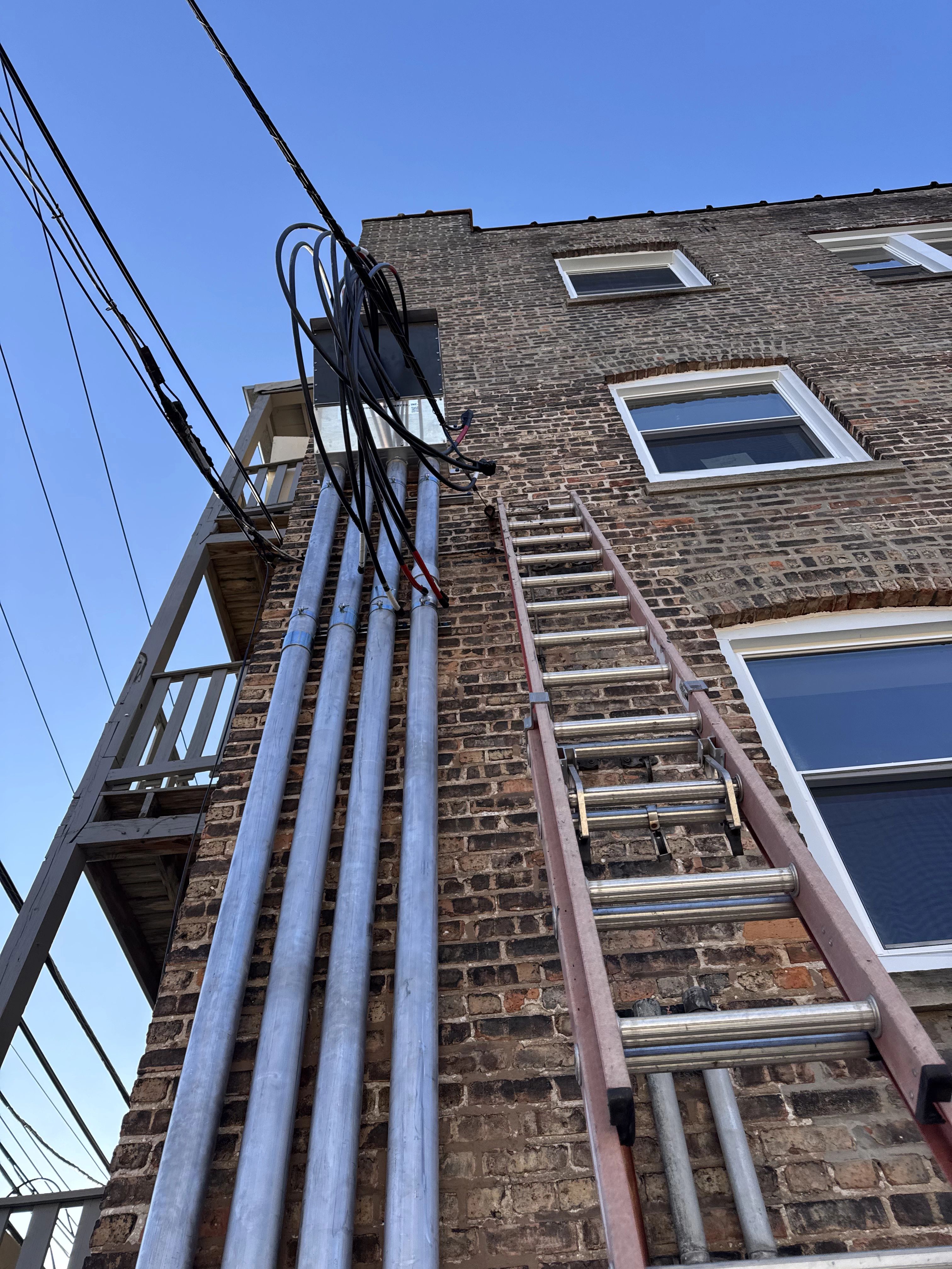 Multiple black wires ready for installation emerging from exterior apartment wall