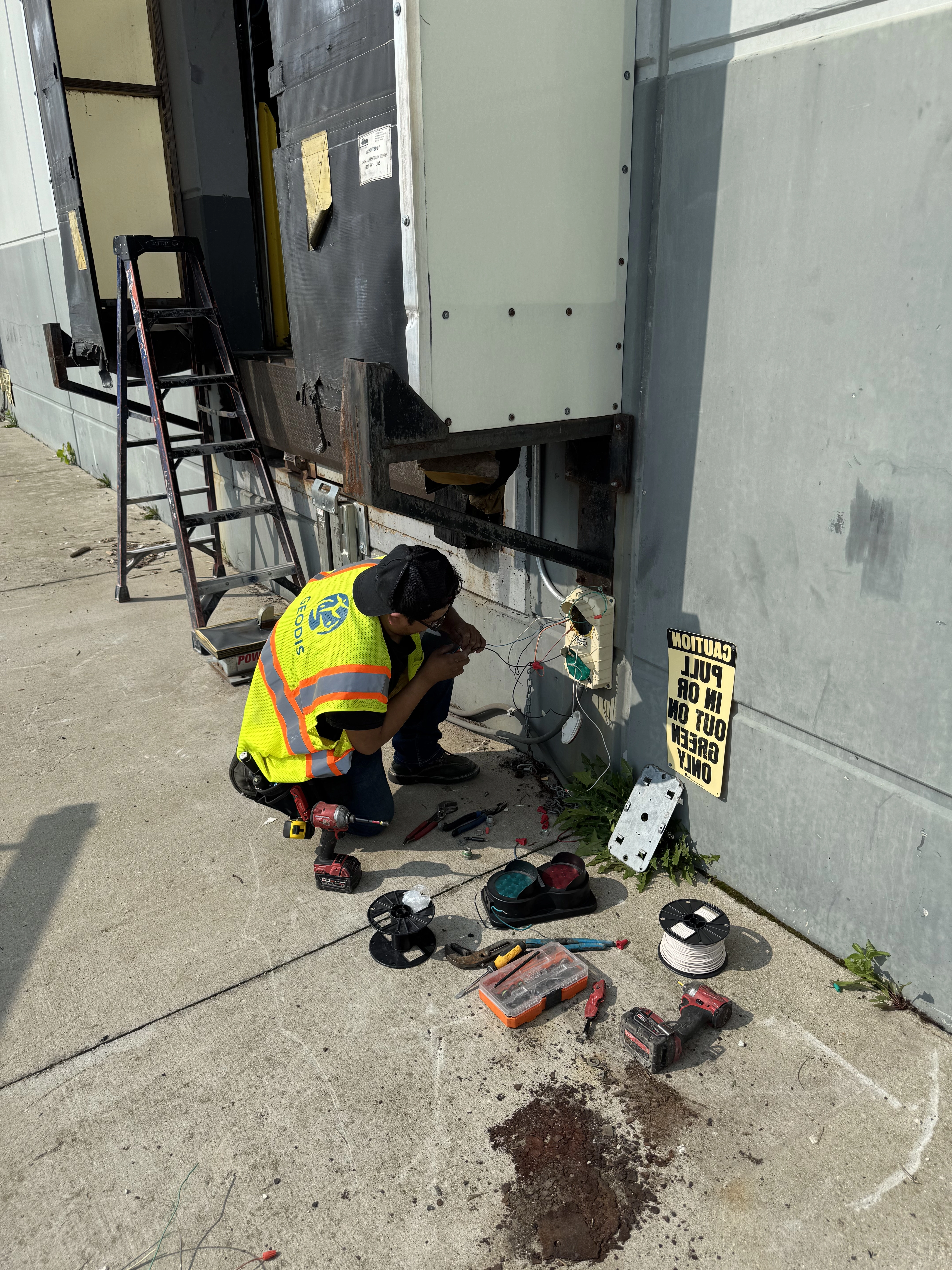 Electrician working on dock lights against a building