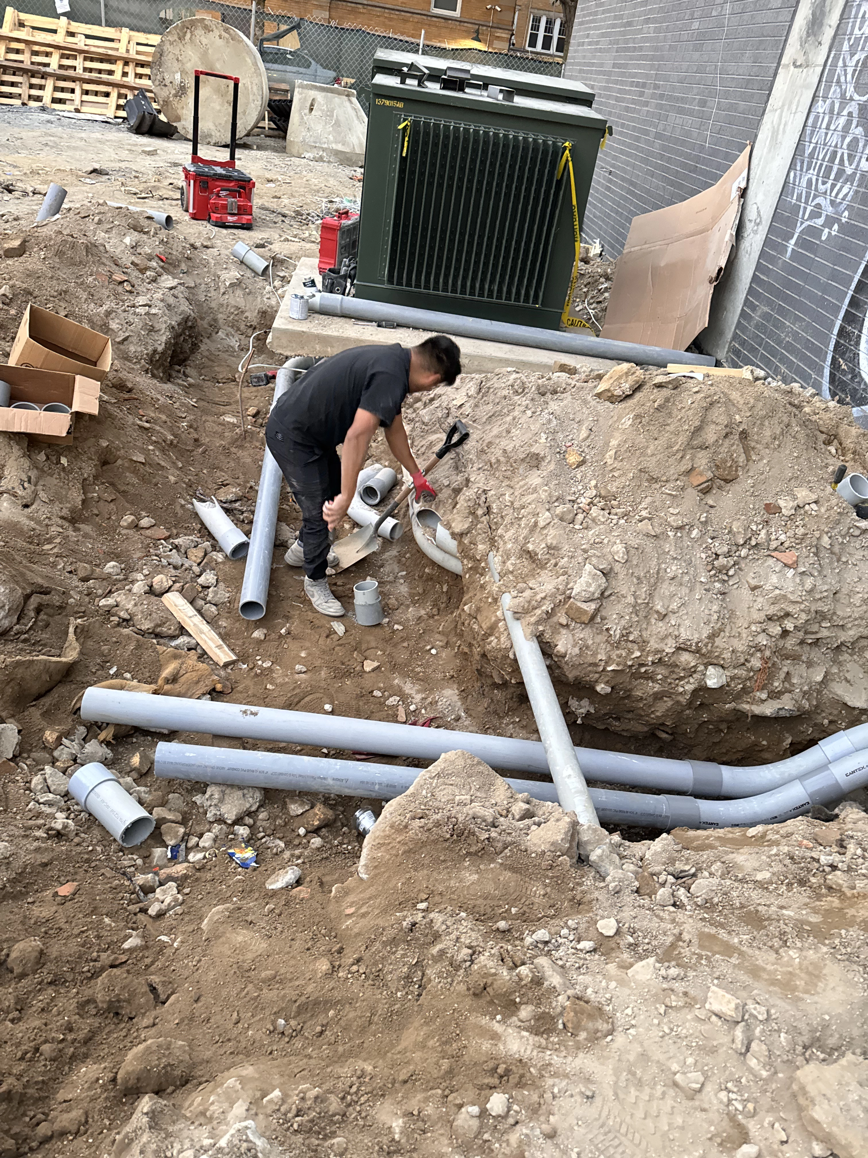 Electrician working outside with pipes for underground electrical wiring