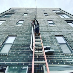GF Electric professional on a ladder against an apartment complex.